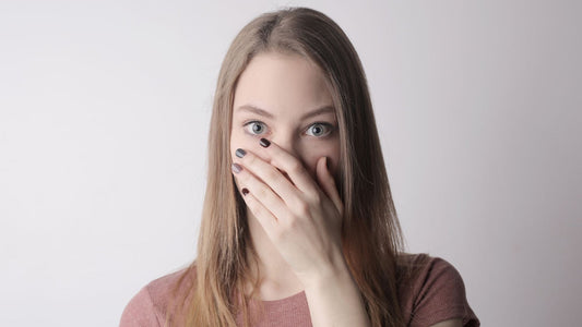 Woman covering her mouth with her hand, eyes wide, worried about bad breath